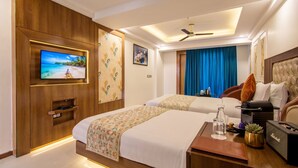 Habitación de hotel con dos camas, televisión, ventilador de techo y minibar.