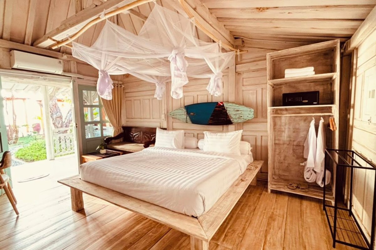 Una habitación de madera con una cama, un banco, un armario y una mesa.
