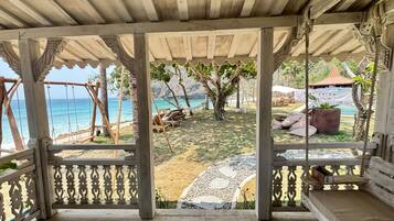 A covered outdoor seating area with a view of the beach and ocean.
