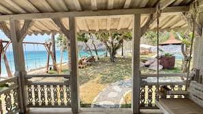 A covered outdoor seating area with a view of the beach and ocean.
