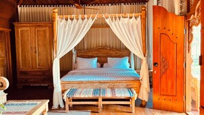 A four-poster bed with a canopy, wooden headboard, and patterned pillows. - Sattura Villa Lawar (Nusa Tenggara Bar.)