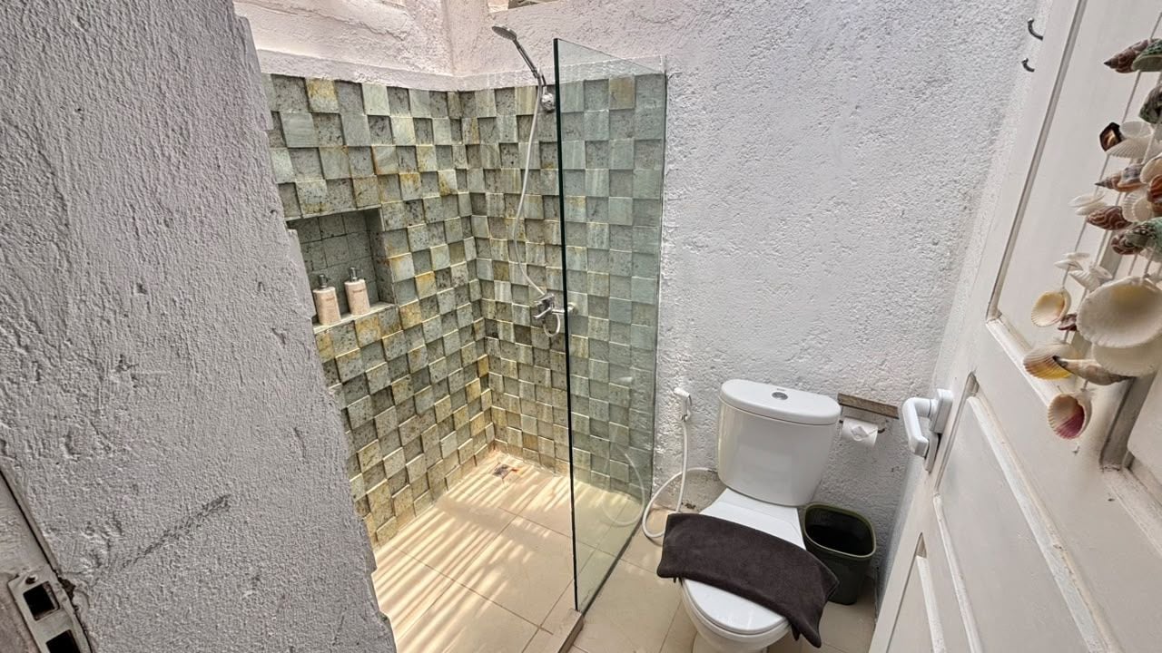 A bathroom with a glass-enclosed shower, a toilet, and a sink.