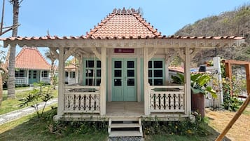 Um edifício em estilo tradicional com telhado de telhas, entrada central com porta verde e varanda com grades.