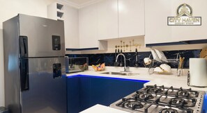 A modern kitchen with a stainless steel refrigerator, a gas stove, and a sink. - City Haven | Luxurious 2BR Home • Modern & Secure (Portmore)