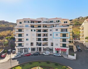 A multi-story residential building with balconies, a supermarket, and a parking area. - ATLANTIC PARADISE II (Caniço)