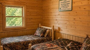 A cabin room with two beds, a ceiling fan, and a window.