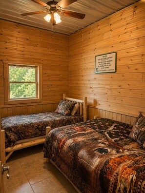 A cabin room with two beds, a ceiling fan, and a window.
