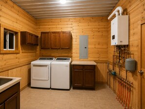 A compact kitchen with wooden walls, a built-in washer and dryer, and a water heater.