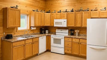 A kitchen with wooden cabinets, a microwave, a stove, and a refrigerator.