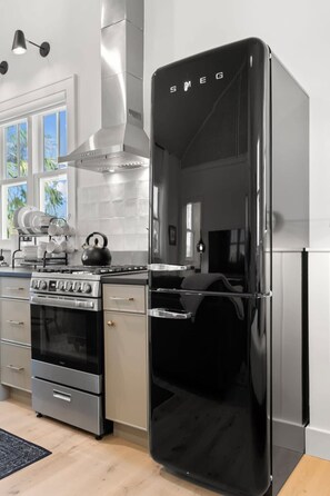 Een moderne keuken met een roestvrijstalen fornuis, oven en een zwarte koelkast.