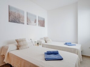 A hotel room with two beds, a bedside table with a lamp, and wall art. - Oliva Nova Cabagua by Interhome (Oliva)