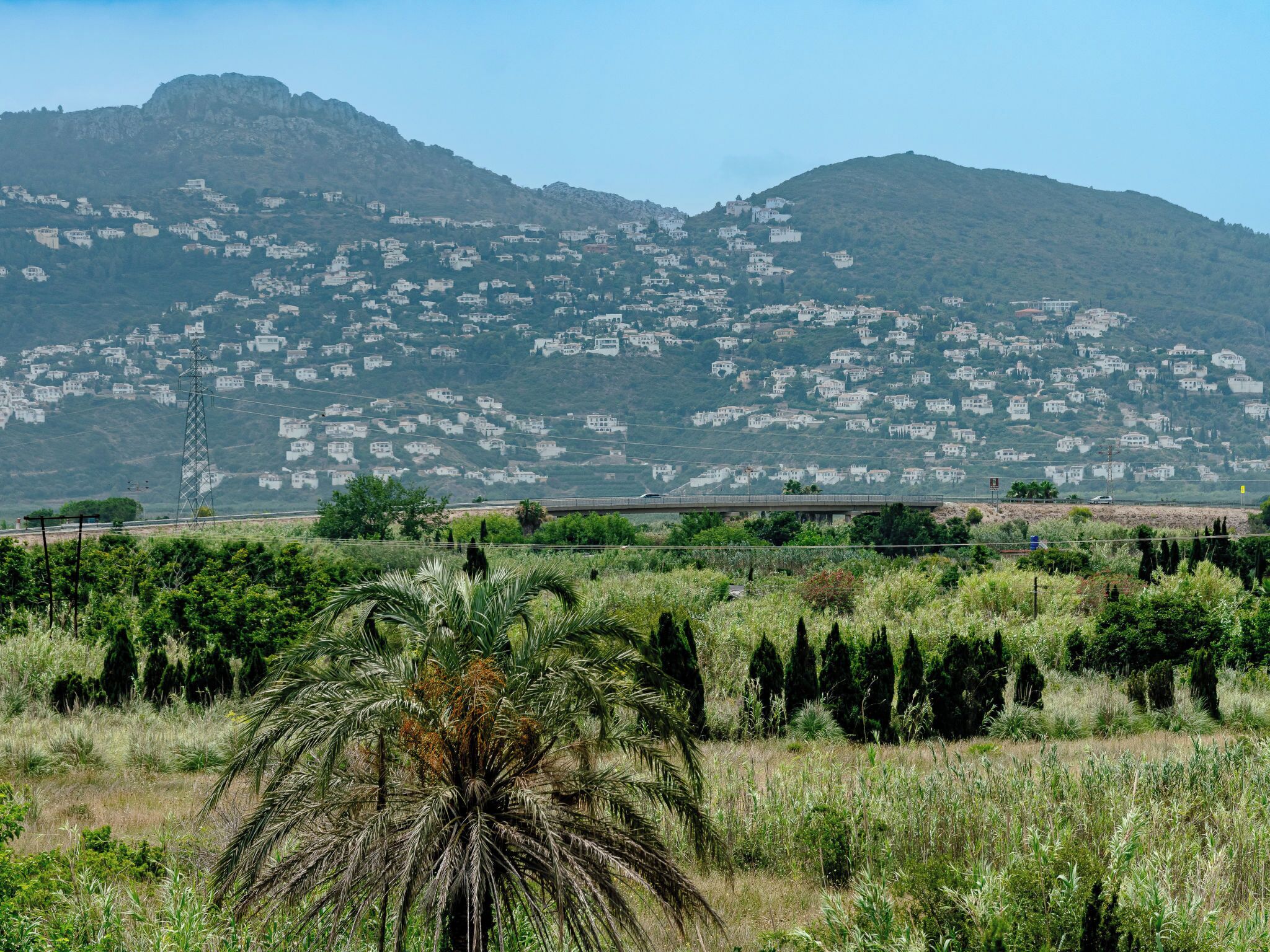 Un paysage rural avec une montagne en arrière-plan et une route au premier plan.