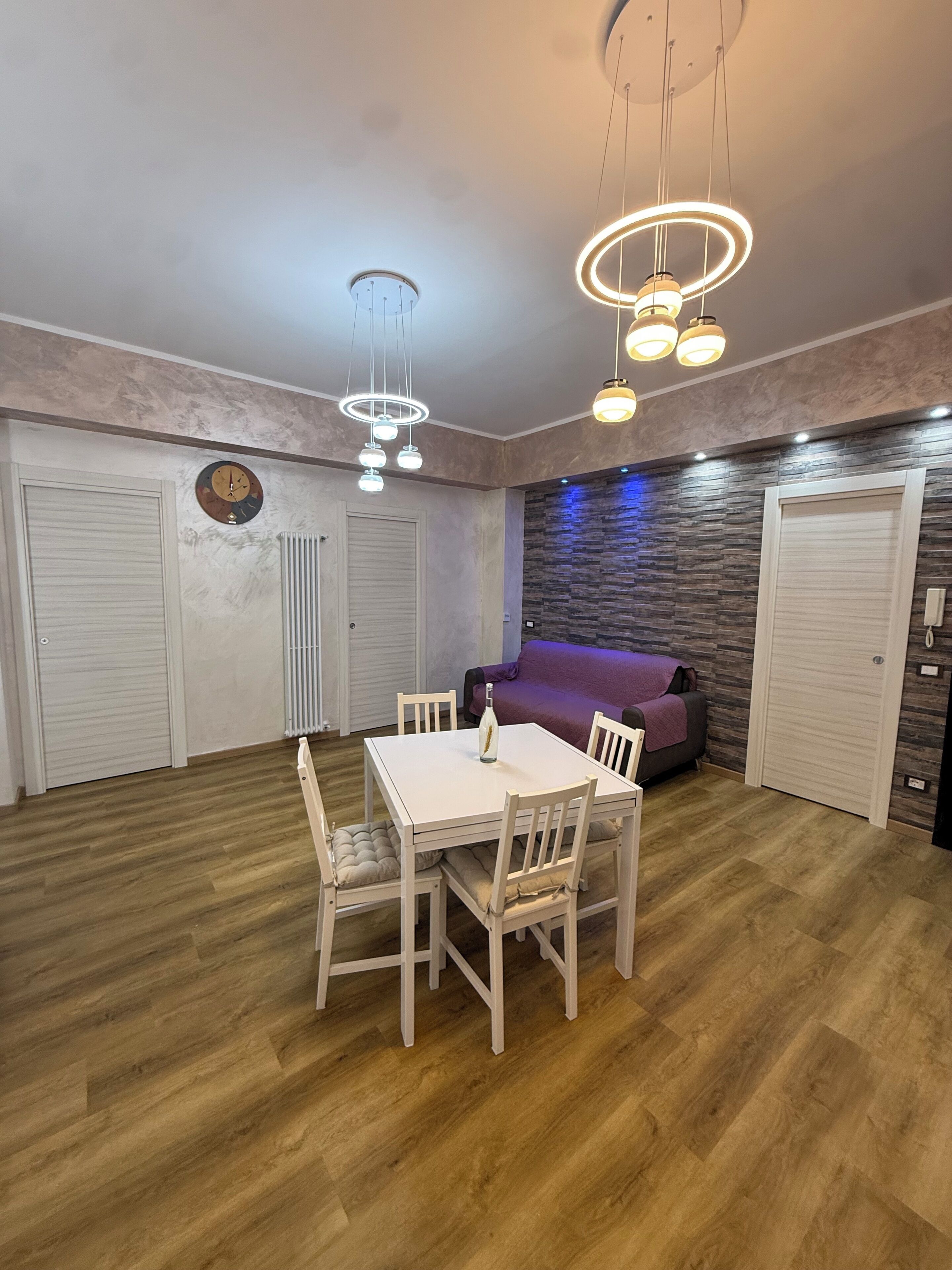 Um quarto com uma mesa de jantar, cadeiras, um sofá e um relógio de parede.