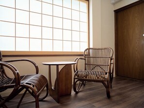 A room with a large window, a wooden floor, and wicker furniture including a chair and a small table. - KONJAKUSO Osaka Bentencho "OKUJO-TEIEN" Rooftop Garden (大阪市港区弁天4丁目)