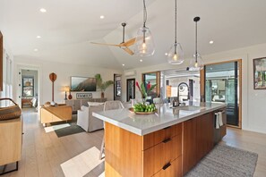 A spacious kitchen with a central island, wooden cabinetry, and pendant lighting. - Luxury Villa in Sunny Poipu with a heated pool, A/C and open floor plan. (Koloa)