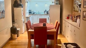 A compact kitchen with a dining area, a small trash bin, and a refrigerator. - Pay30nghts get up tp extra 59 free (Greater London)