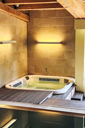 A spa room with a freestanding bathtub, wooden ceiling beams, and a tiled wall. - Wellness Retreat Labská by Interhome (Spindleruv Mlyn)