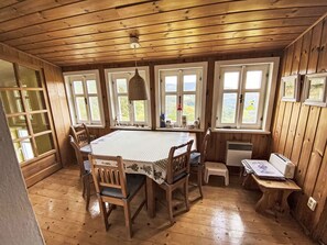 Ein Esszimmer aus Holz mit einem Tisch, Stühlen und Blick durch die Fenster.