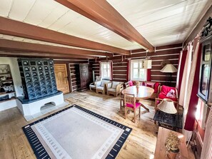 Interior de una cabaña de troncos con comedor, asientos y chimenea.