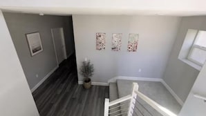 A stairwell with a grey wall, a potted plant, and three framed pictures. - Breathtaking Modern Hillside Suite (San Jose)
