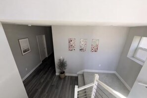 A stairwell with a grey wall, a potted plant, and three framed pictures. - Breathtaking Modern Hillside Suite (San Jose)