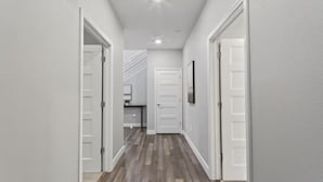 A hallway with white walls and wooden flooring leading to a door. - Breathtaking Modern Hillside Suite (San Jose)