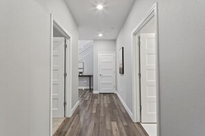 A hallway with white walls and wooden flooring leading to a door. - Breathtaking Modern Hillside Suite (San Jose)