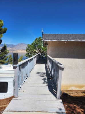 Un escalier en bois mène à un bâtiment d’où l’on a une vue sur les montagnes et un lac.