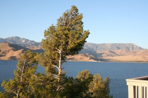 A clear view of a lake with mountains in the background and trees in the foreground.