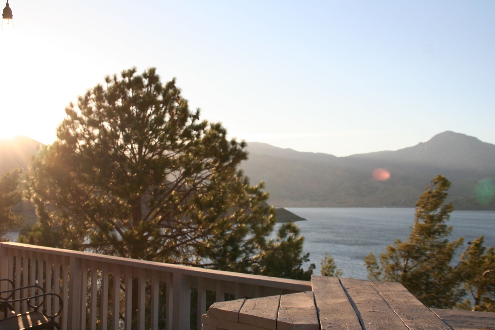 A wooden deck with a view of a lake and mountains in the background.