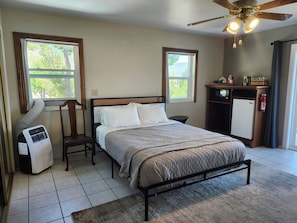 Une chambre à coucher comprenant un lit, un bureau, une chaise, un radiateur et un ventilateur de plafond.