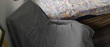 A small bedroom with a bed, a bedside table, a lamp, and a wall-mounted painting.