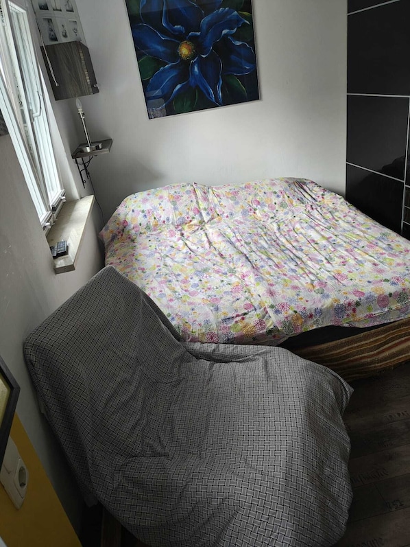 Un dormitorio pequeño con una cama, una mesita de noche, una lámpara y un cuadro en la pared.