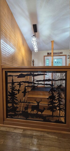 A wooden staircase with a forest-themed cutout design. - Beautiful Modern Cabin in the woods (Daniels)