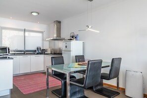 A modern kitchen with white cabinets, a stainless steel range, a coffee maker, and a wine cooler. - Casa Laranja – Stunning Ocean Views & Hot Tub (Fajã da Ovelha)