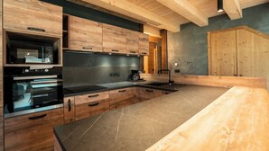 A modern kitchen with wooden cabinets, a large island, and built-in appliances. - 2-Bedroom Apartment with Mountain Views (Châtel)