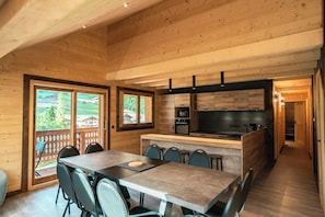 Eine moderne Küche mit Holzschränken, einer zentralen Kochinsel und einem Essbereich mit Tisch und Stühlen.