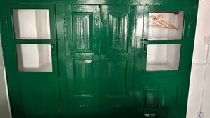 A green door with two windows and a small shelf with hangers.