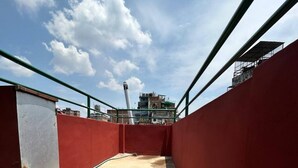 A rooftop terrace with a red wall, a metal door, and a concrete floor.