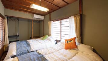 Una habitación con cama, armario y ventana con cortinas.