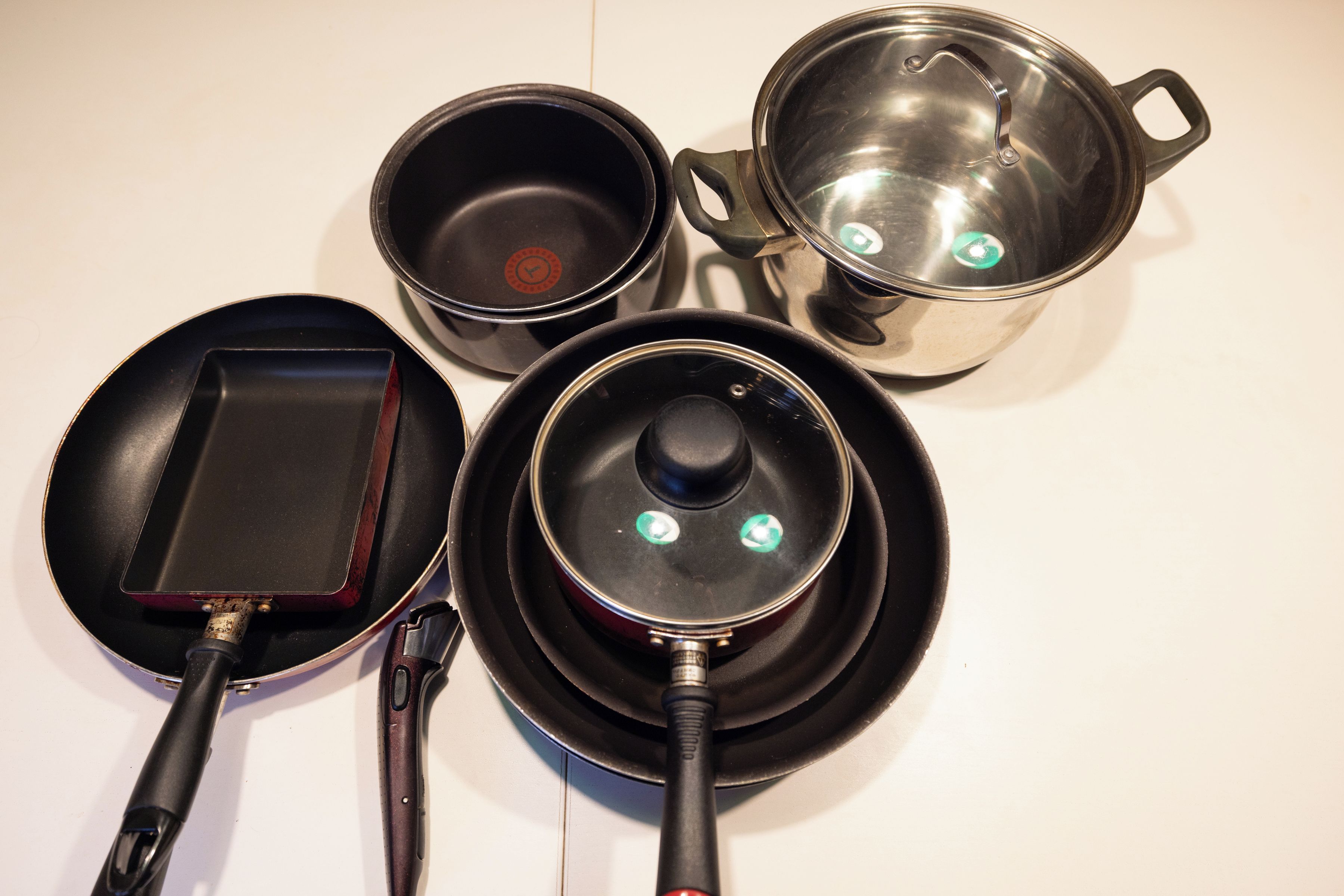A kitchen with a frying pan, a pot, and a pan on a stove.