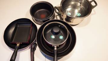 A kitchen with a frying pan, a pot, and a pan on a stove.