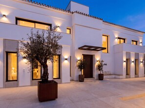 A modern building with large windows, a central entrance, and potted plants. - Villa Confort by Vacation Marbella (Estepona)