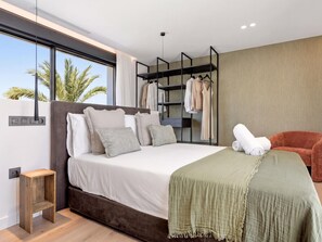 A modern bedroom with a large bed, a built-in wardrobe, and a seating area. - Villa Confort by Vacation Marbella (Estepona)