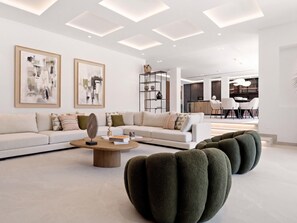 A modern living room with a sectional sofa, a coffee table, and a unique green pouf. - Villa Confort by Vacation Marbella (Estepona)