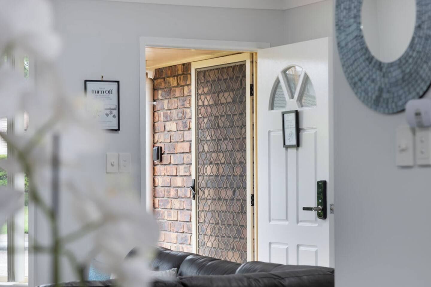 A room with a brick wall, a white door, and a black leather sofa.