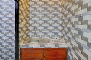A bathroom with a tiled backsplash, a sink, and wooden cabinets. - Cozy Standard Room in Badung (Mengwi)
