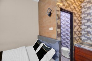 A hotel room with a bed, a bathroom with a tiled wall, and a door leading to another room. - Cozy Standard Room in Badung (Mengwi)