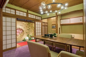 Ein traditioneller japanischer Raum mit Tatami-Bodenbelag, einem Holztisch und einem Shoji-Bildschirm.