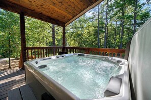 A hot tub on a wooden deck with a view of a forest. - Sweet Magnolia Cabin with Hot Tub and Fire Pit (Broken Bow)